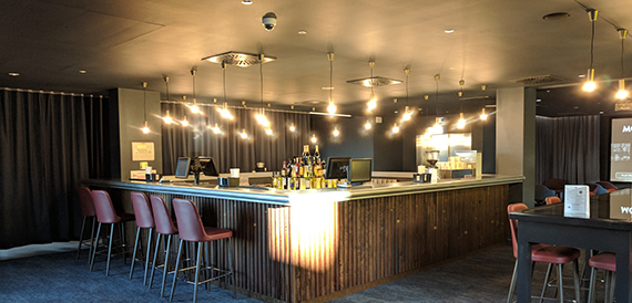 Bar counter with hanging bulb lights and red stools