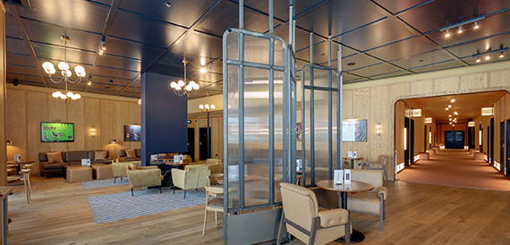 Lounge with a glass partition and beige armchairs near screen corridors