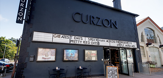 Curzon's dark exterior with a film title marquee and outdoor tables