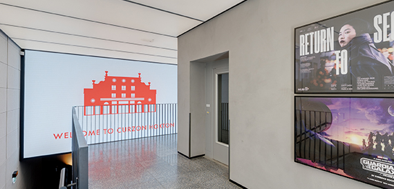 Corridor with a digital welcome screen and framed film posters