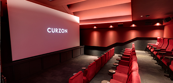 Red-themed screening room with velvet seats facing an illuminated screen