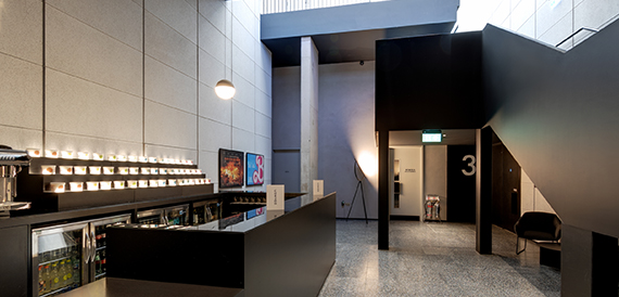 Ticket counter with illuminated displays beside a concrete stairwell
