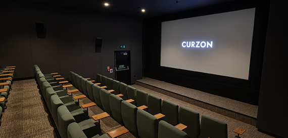 Screening room with green seats and fold-down tables facing the screen