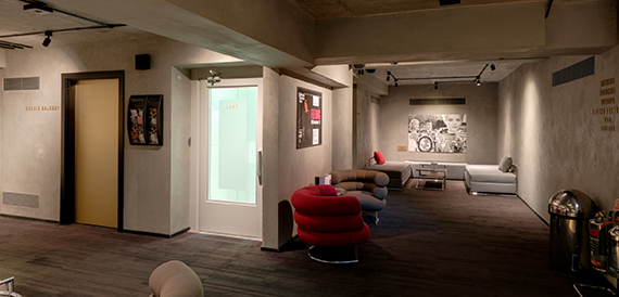 Lounge with red curved armchairs, sofas and dim ceiling lighting