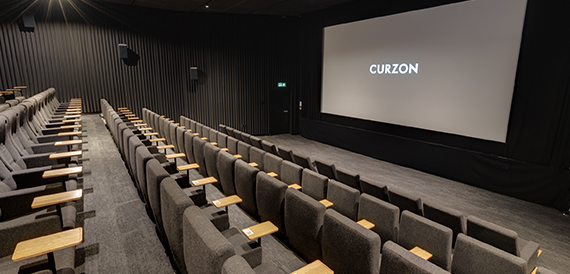 Cinema screening room with grey seats and a glowing Curzon screen