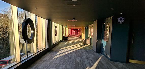 Corridor with a circular window feature overlooking a red-carpeted room