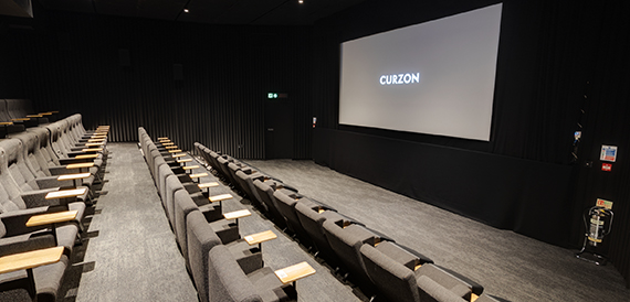 Cinema screening room with grey tip-up seats and fold-down side tables