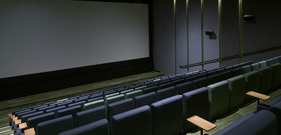 Cinema screening room with green and blue seats beside gold accent poles