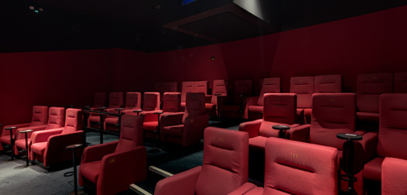 Cinema auditorium with red seats and glowing armrest numbers