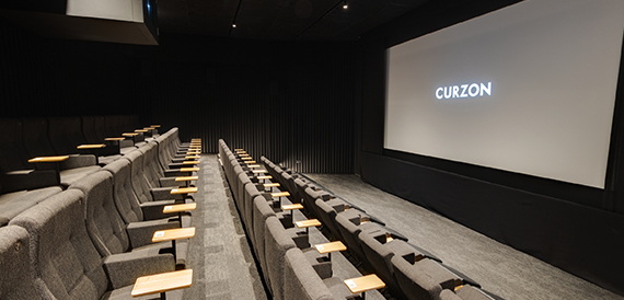 Cinema screening room viewed from the back row toward a lit screen
