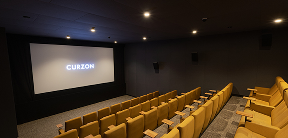 Cinema auditorium with mustard yellow seats and a glowing screen