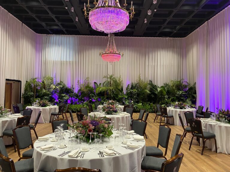 Banqueting Suite with round tables, purple lighting and a hanging chandelier