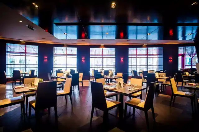 Brasserie Joel dining room with wood chairs and blue-lit curved windows