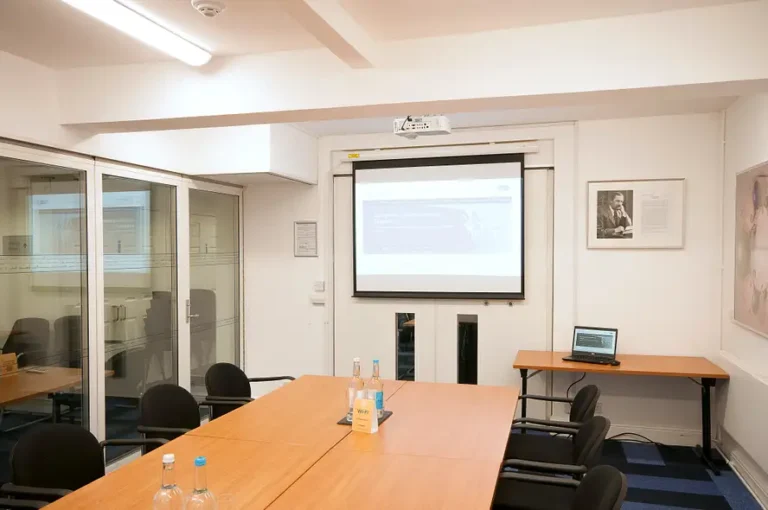 Burnside Room with a long table facing a pull-down projector screen