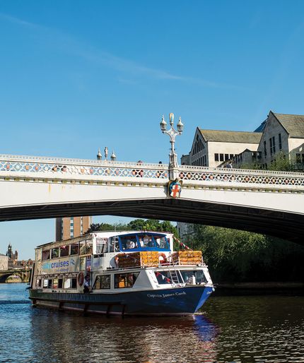 Captain James Cook boat sailing beneath a lamp-post bridge in sunshine