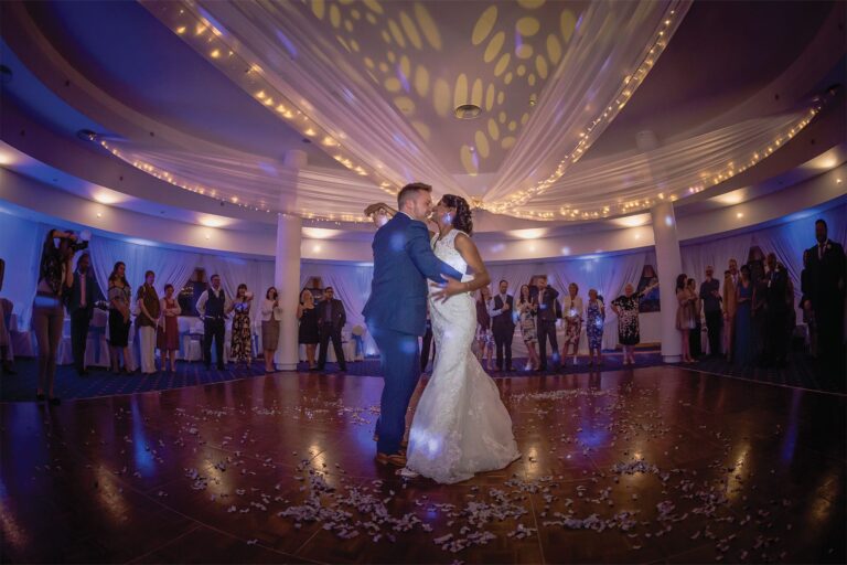 Couple dancing on the Clubhouse Ballroom floor beneath a draped fairy-light ceiling