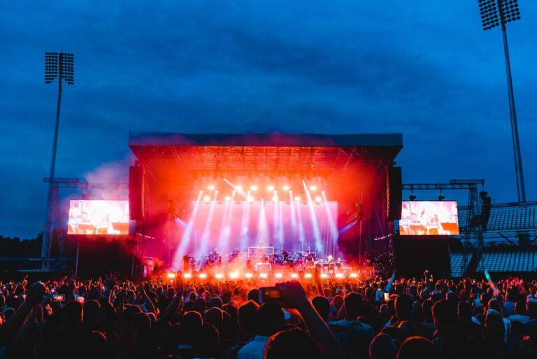 Outdoor concert stage lit with colourful lights and a large crowd
