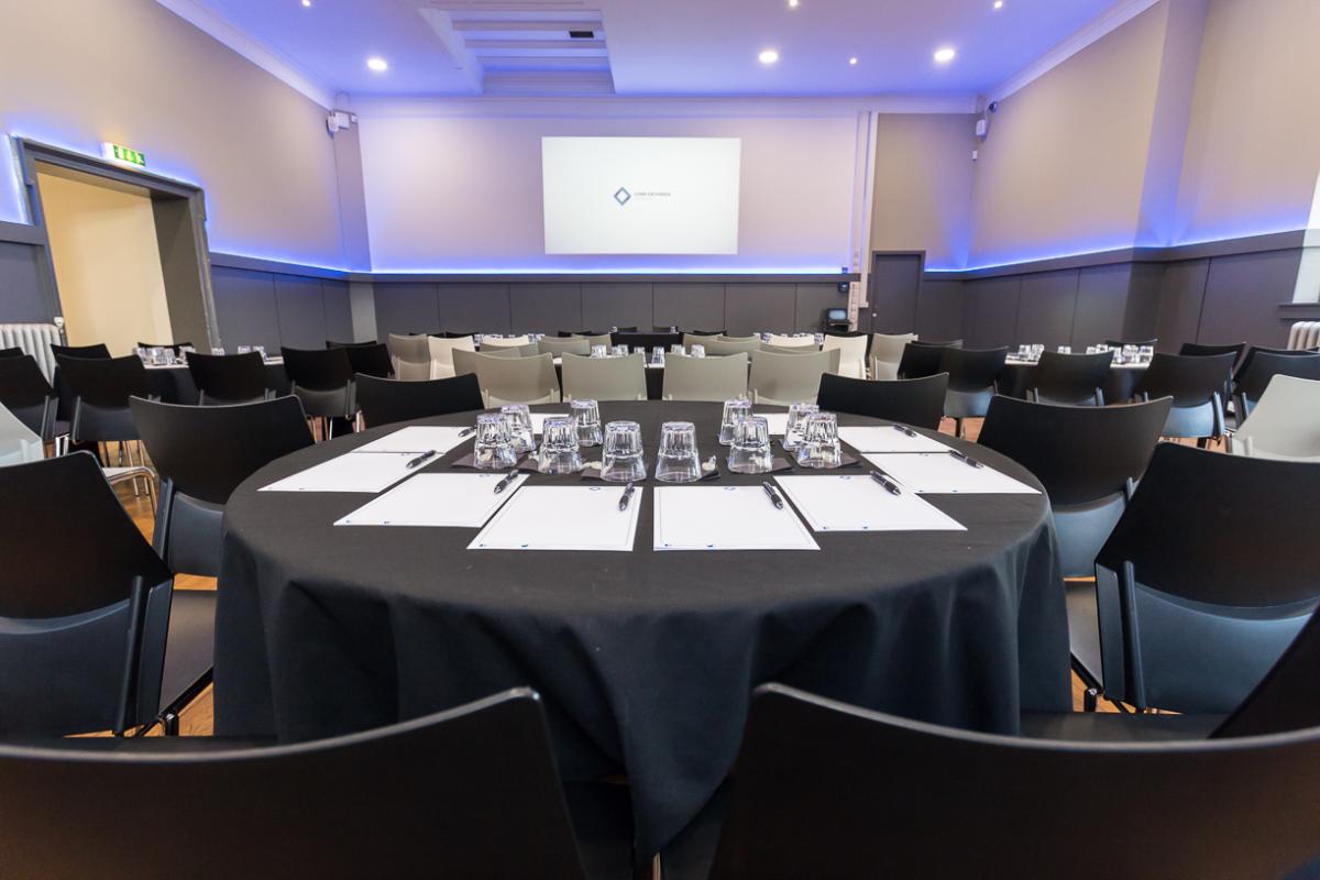 Conference room with a round table set for delegates and a screen