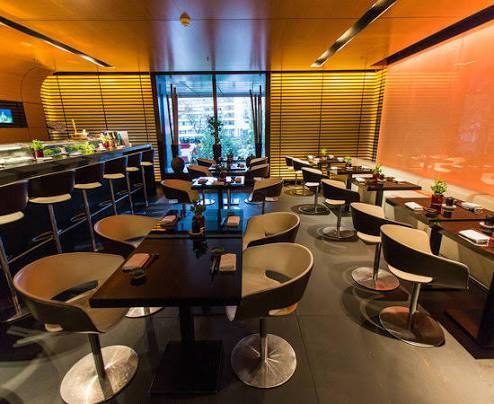 Ichi Sushi bar seating with an orange lit wall and city view windows