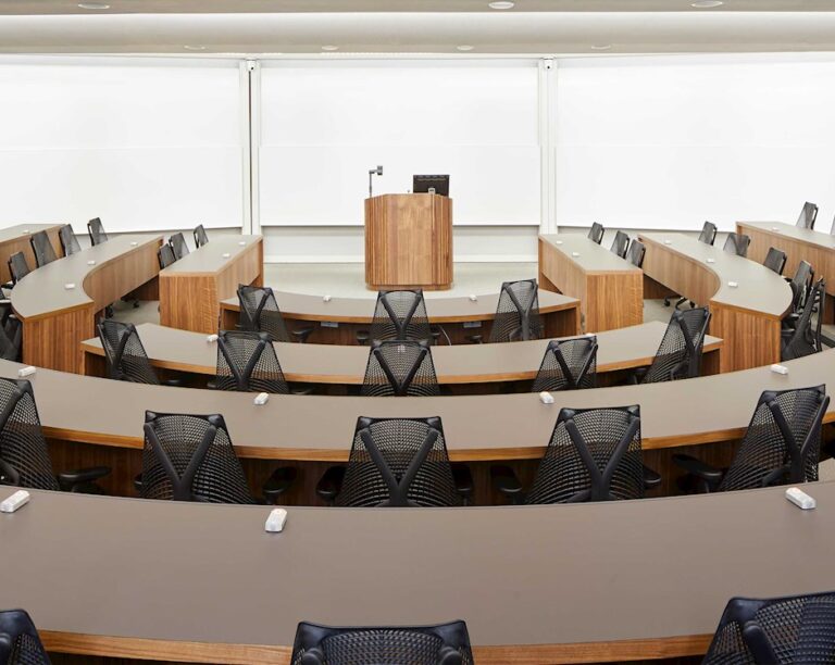 Tiered lecture theatre with curved rows of desks facing a wooden lectern