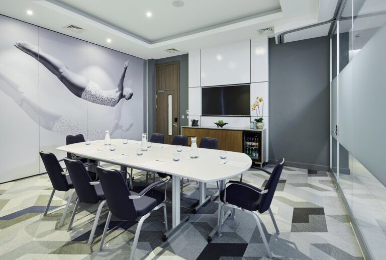 Boardroom table set beneath a mural of a diver, with a wall screen