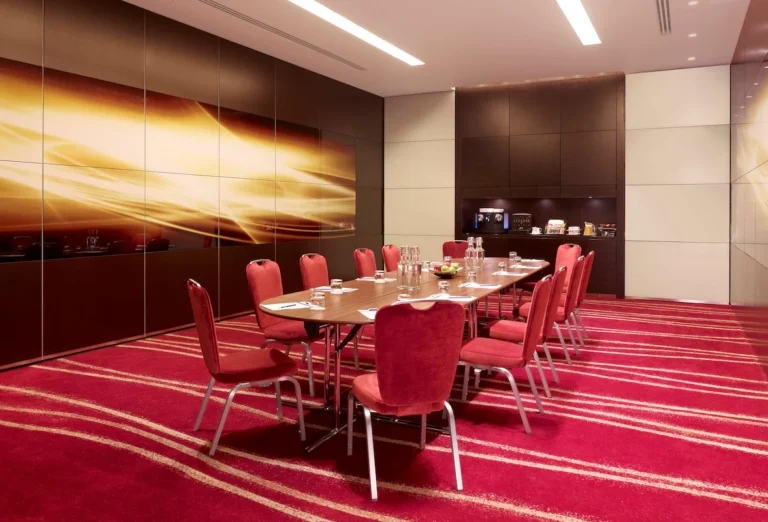 Plaza Suite boardroom with red chairs and an orange abstract wall mural