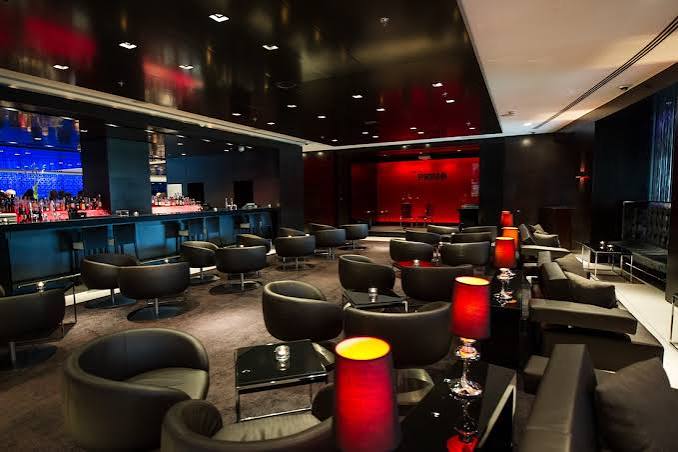 Primo Bar lounge area with black armchairs and red accent tables