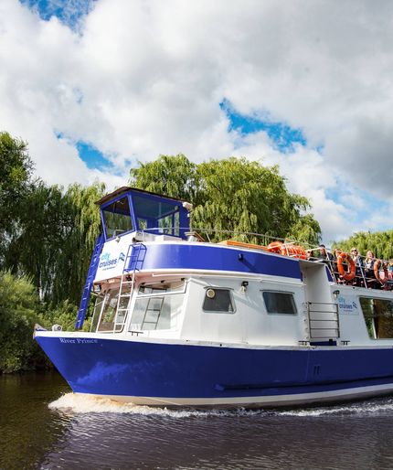 River Prince boat cruising past willow trees on the water