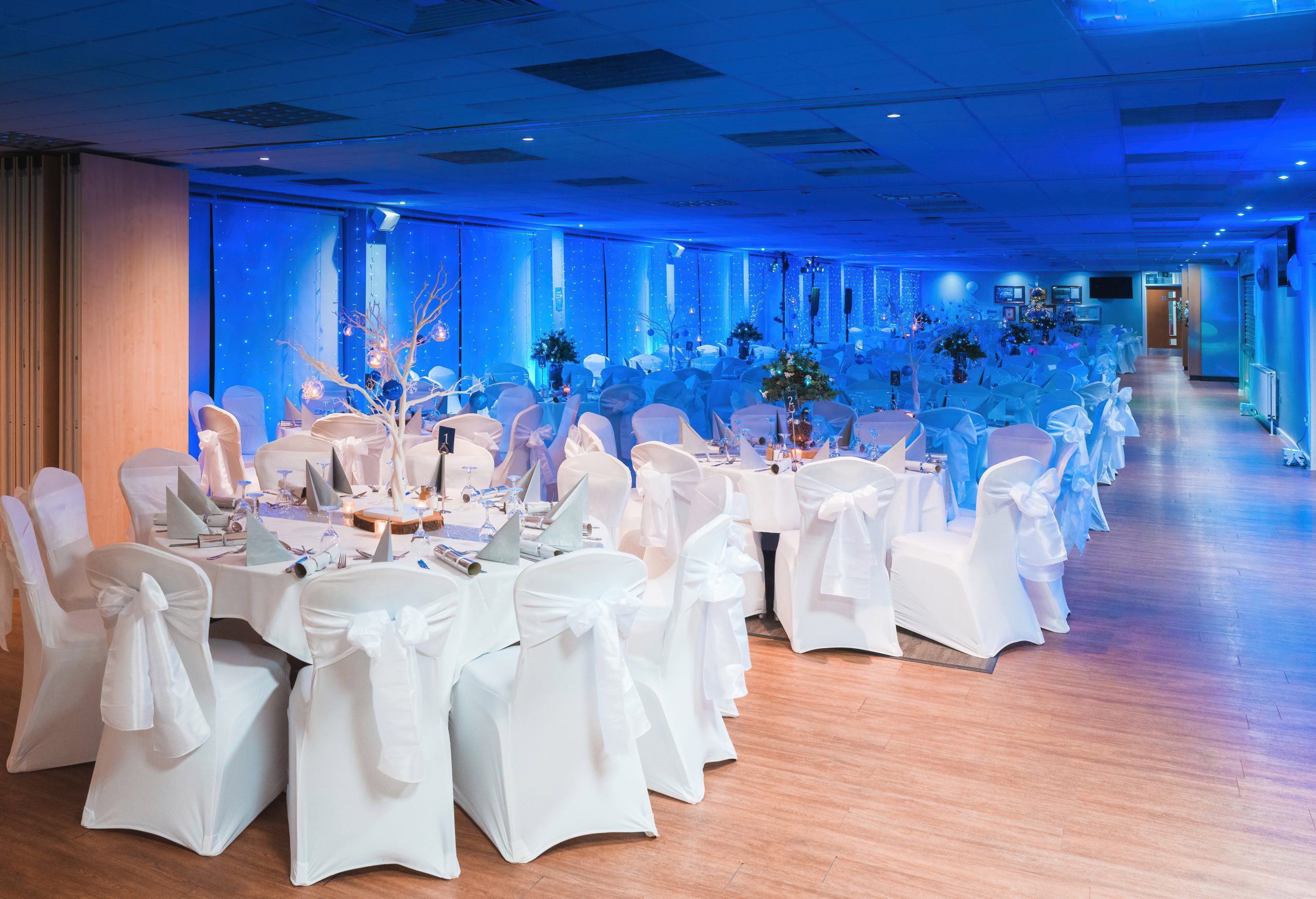 Function room set for a wedding with round tables in white chair covers