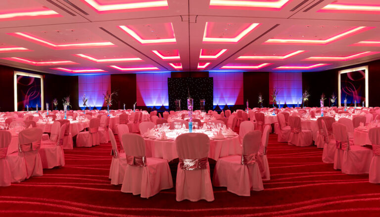 Ballroom banquet layout with round tables seen from the stage end