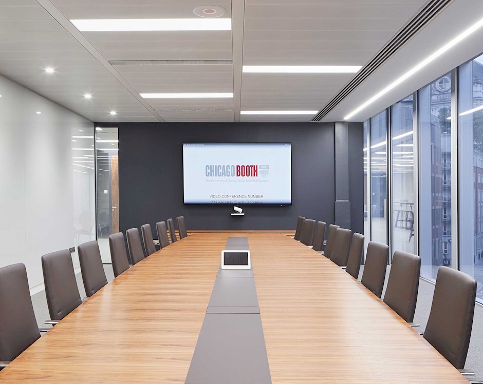 Boardroom with a long table, black leather chairs and a wall screen