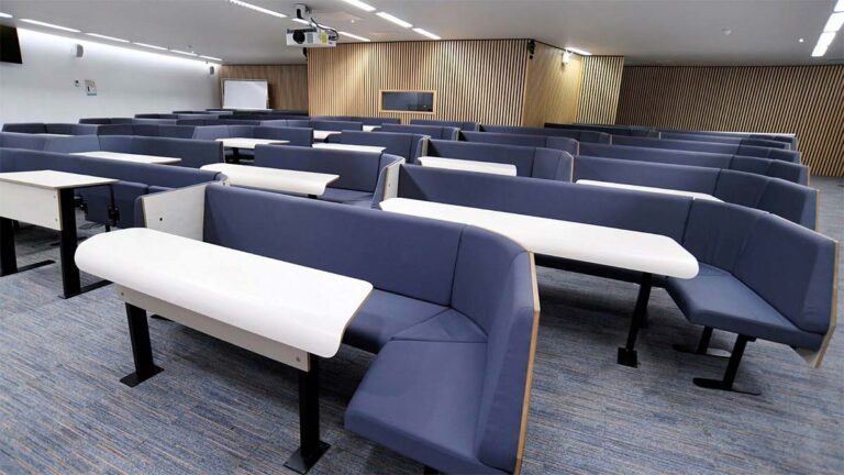 Curve lecture theatre with tiered blue bench seating and fold-out desks