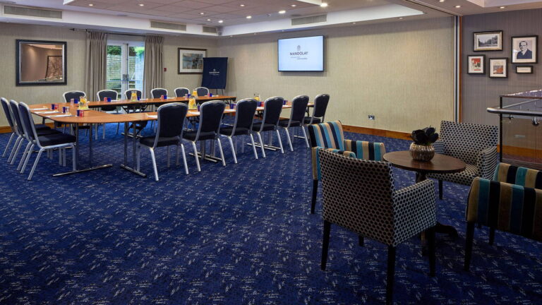 Epsom Room set boardroom-style with a U-shaped table and screen