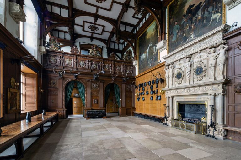 Great Hall with dark wood panelling, an ornate fireplace and oil paintings