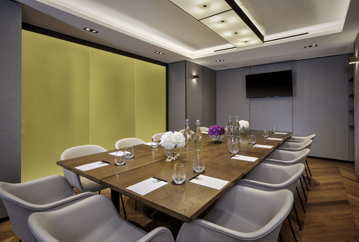 The London Room laid out for private dining with a wooden table and flowers.