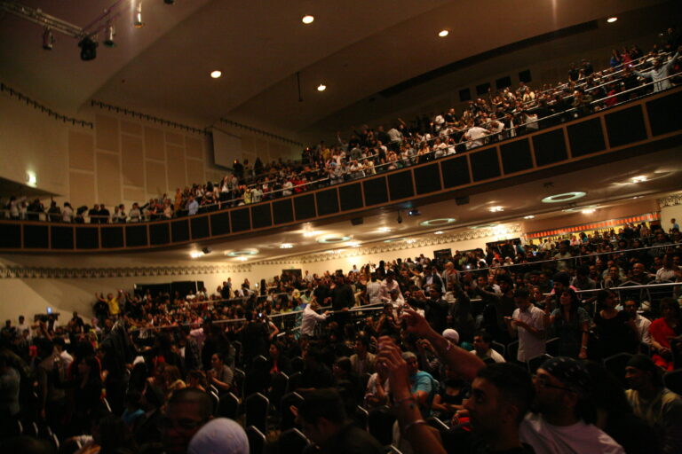 Packed balcony seating viewed from the stage during a live event